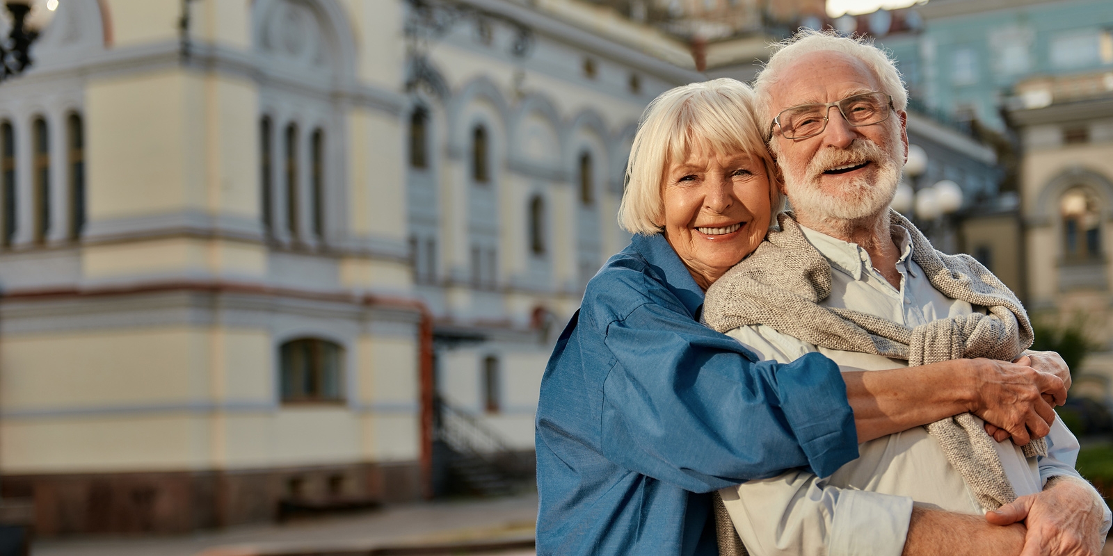 elderly couple hugging and smiling at camera