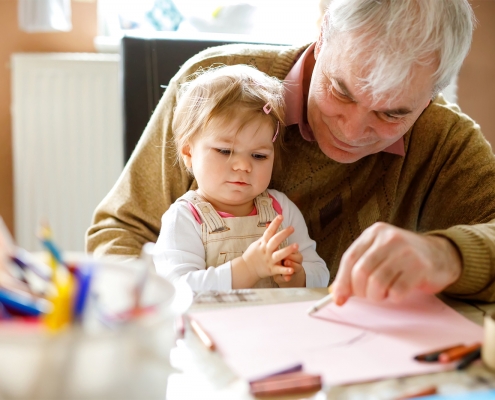 elderly man drawing a picture with a baby