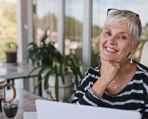 elderly woman smiling while at her laptop